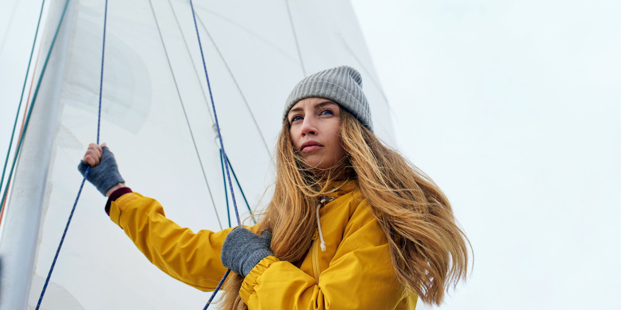 Frau mit gelber Windjacke segelt